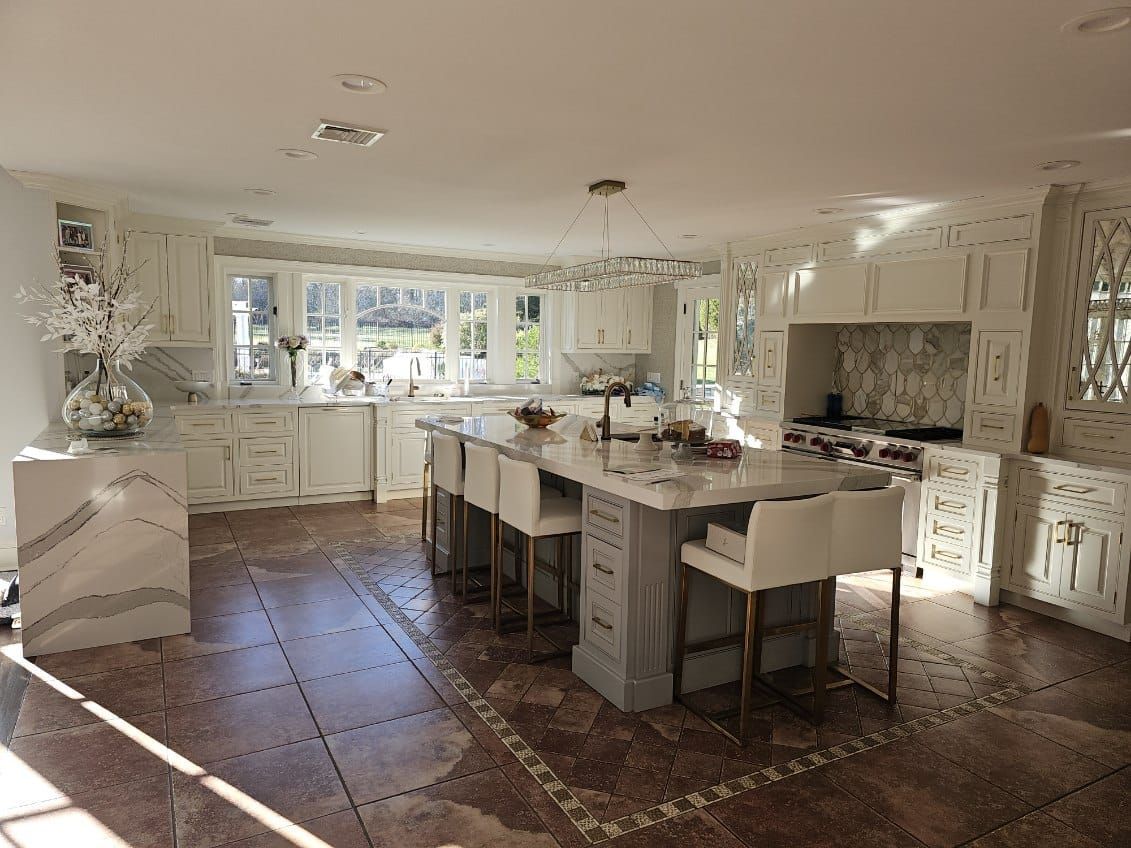 A large kitchen with white cabinets and a large island in the middle.