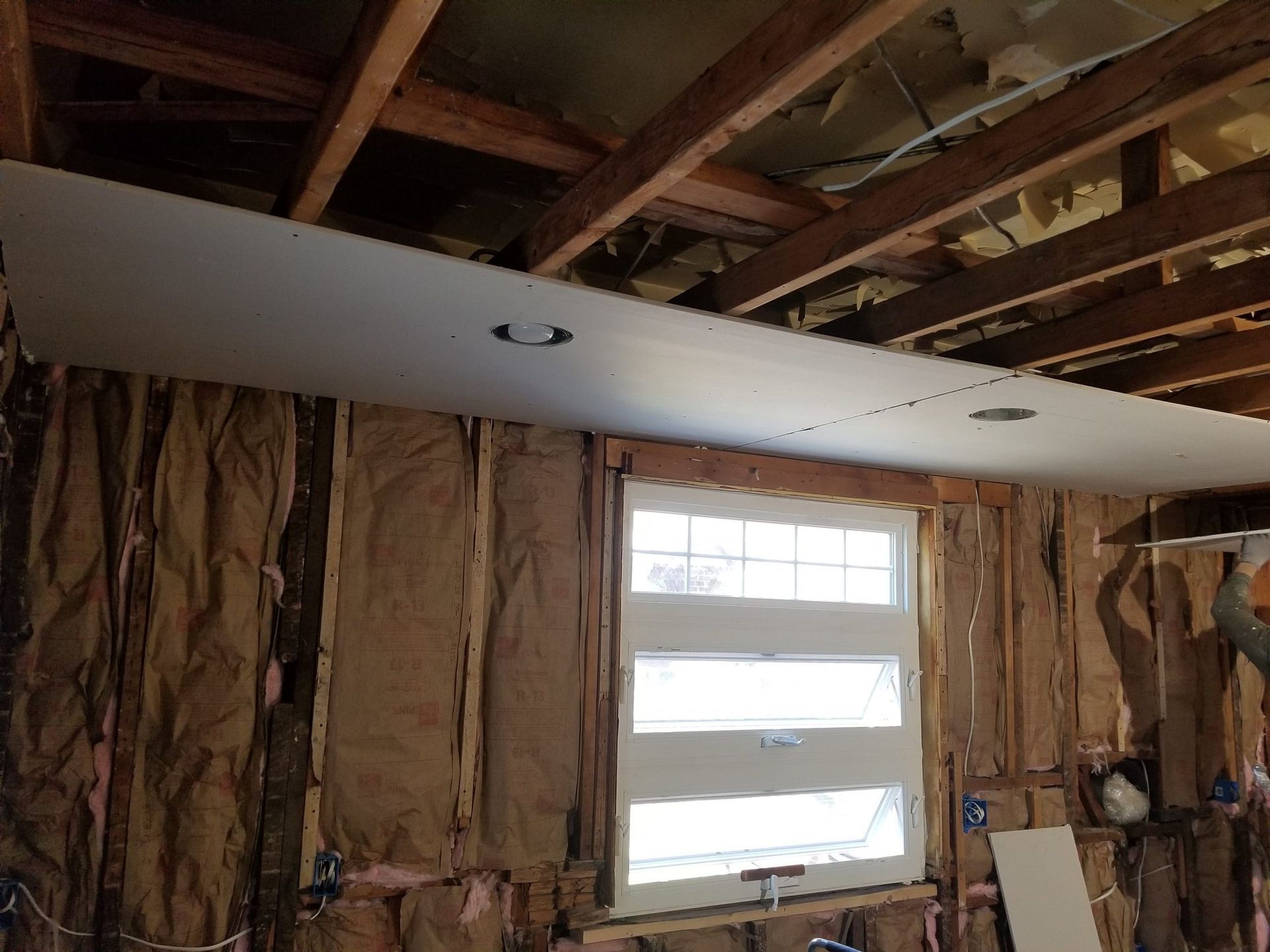 A room with a window and a ceiling that is being remodeled.