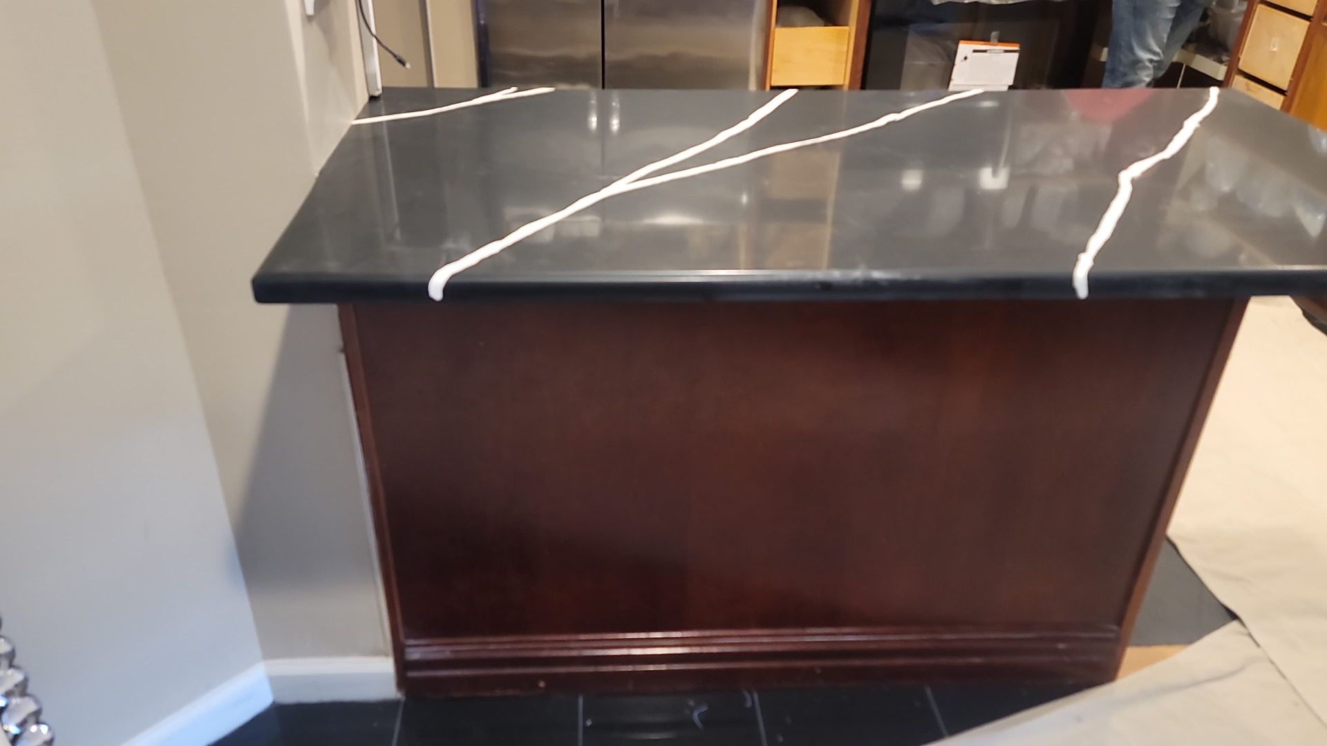 A kitchen island with a black granite counter top and a wooden cabinet.