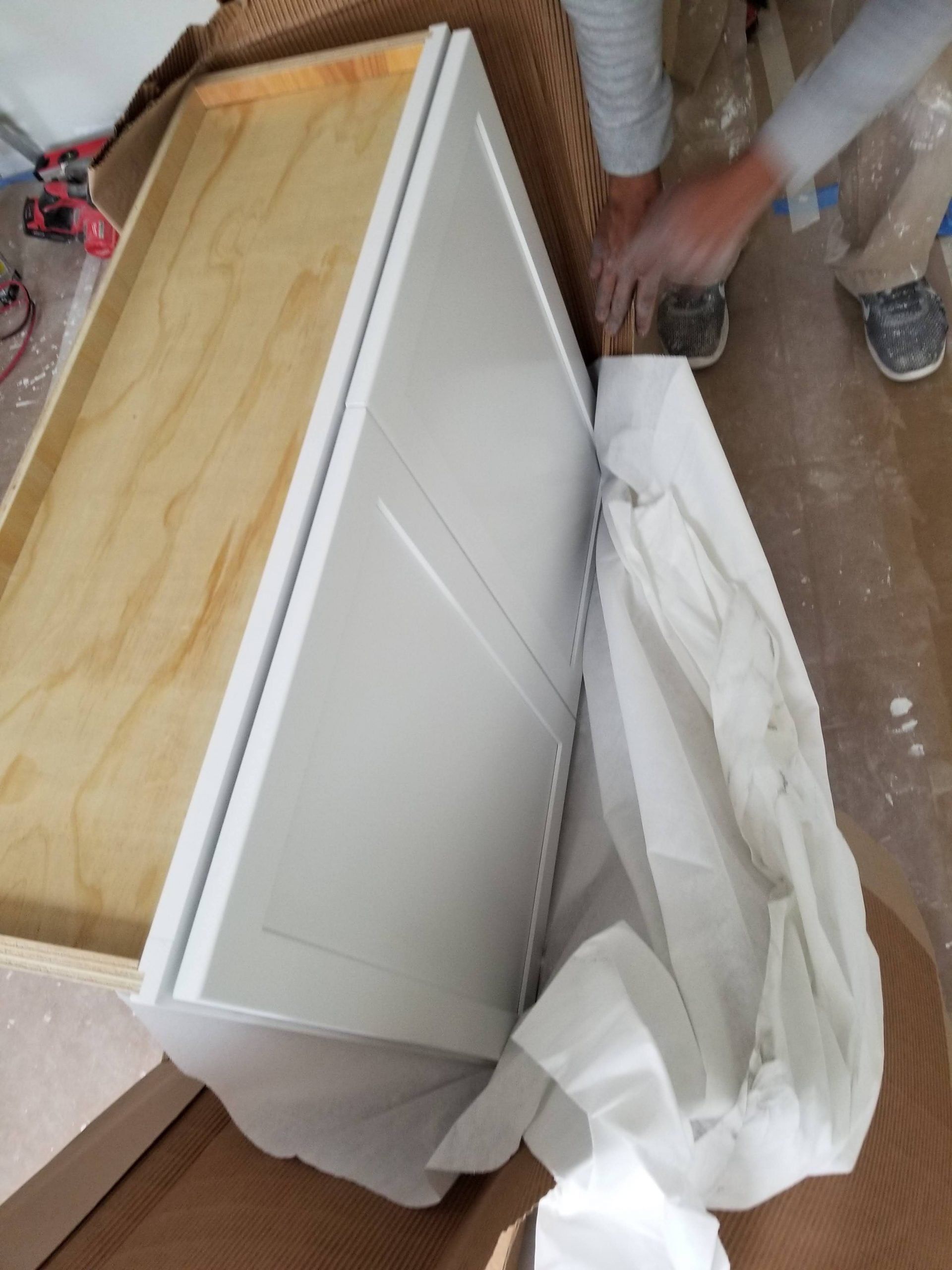 A person is working on a white cabinet with a wooden top