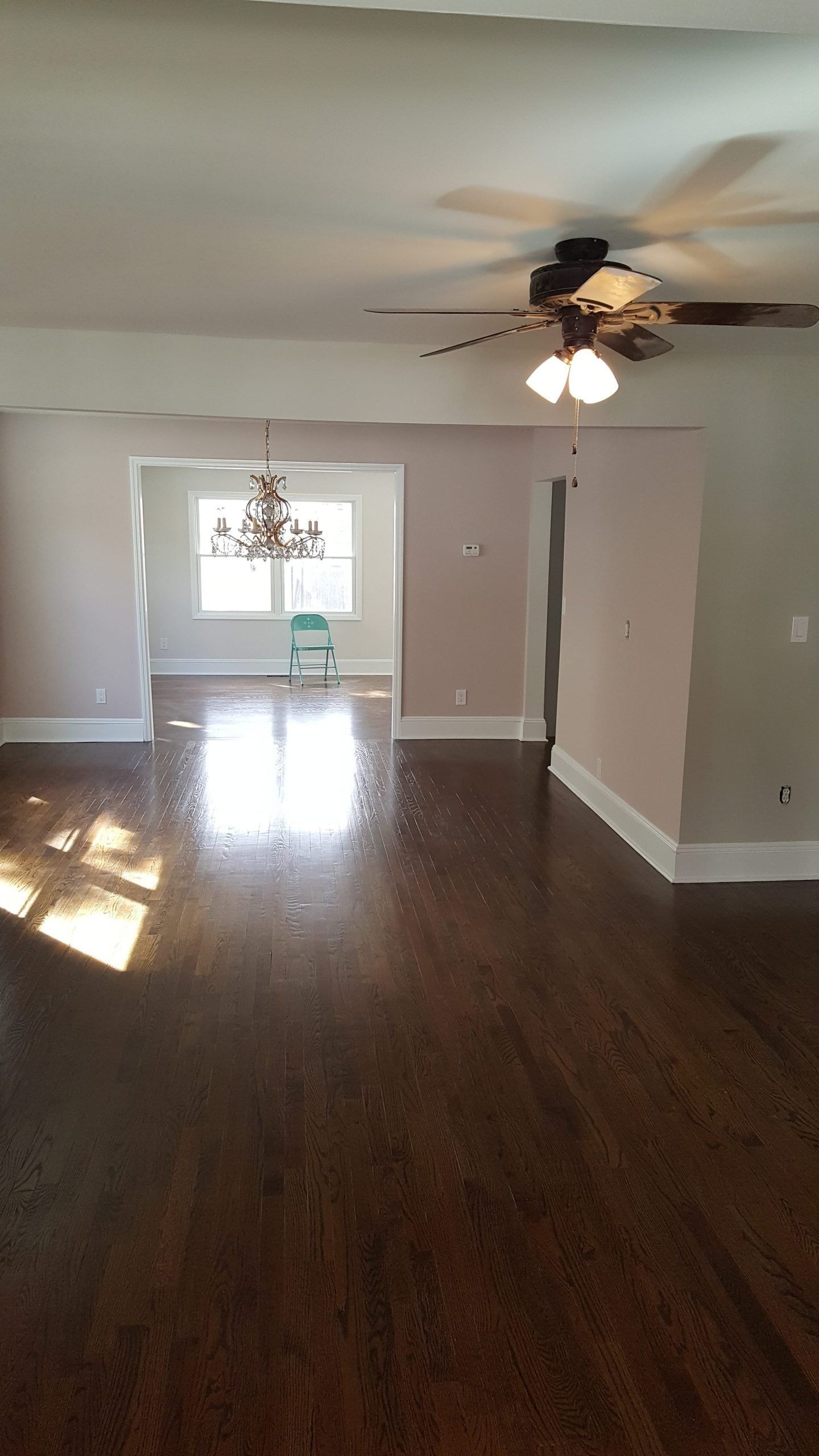 An empty living room with hardwood floors and a ceiling fan.