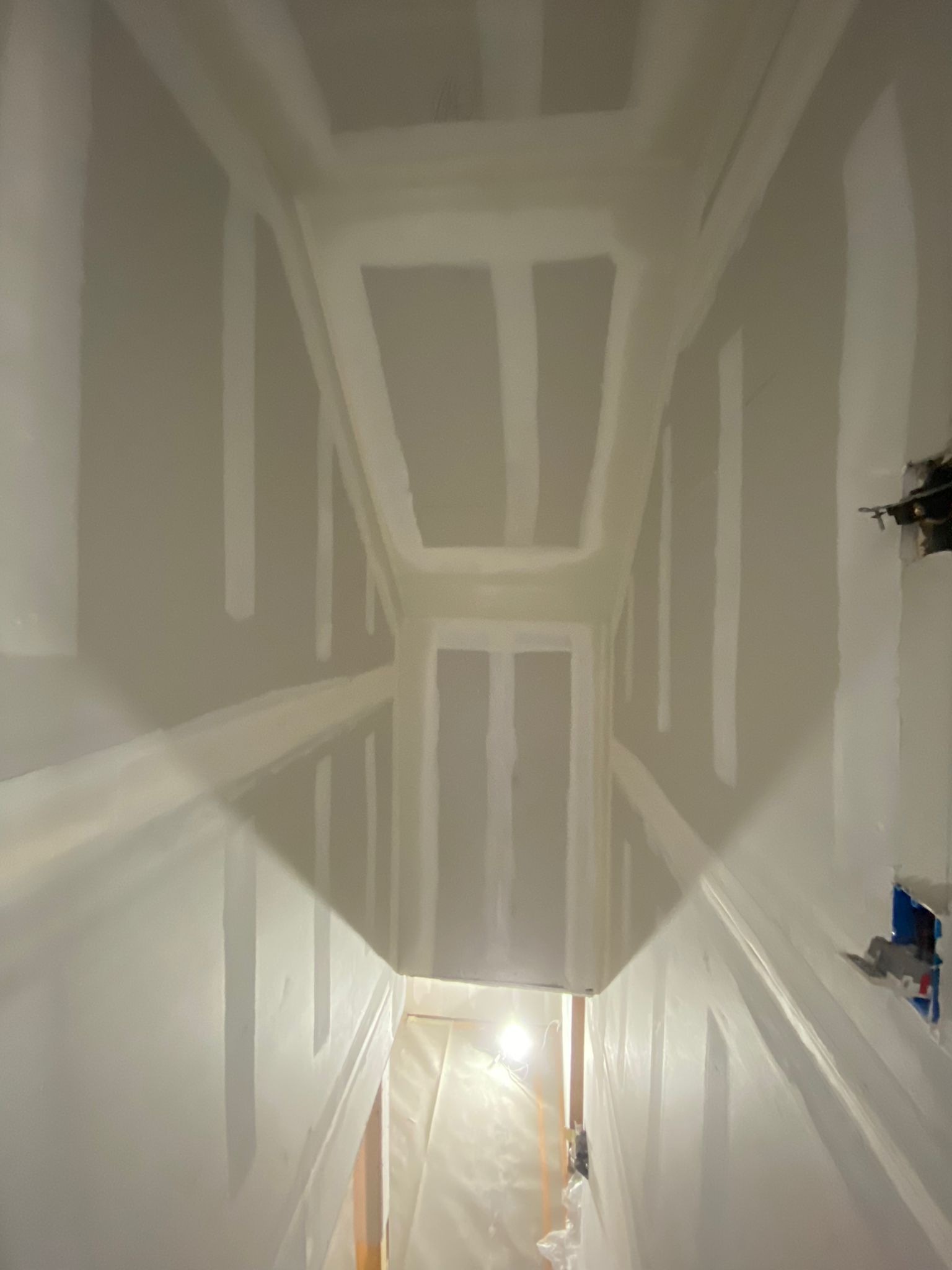 A hallway with a ceiling that is being painted white.