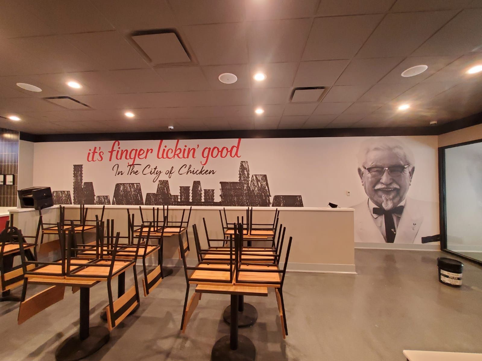 An empty restaurant with tables and chairs and a sign that says it 's finger lickin ' good