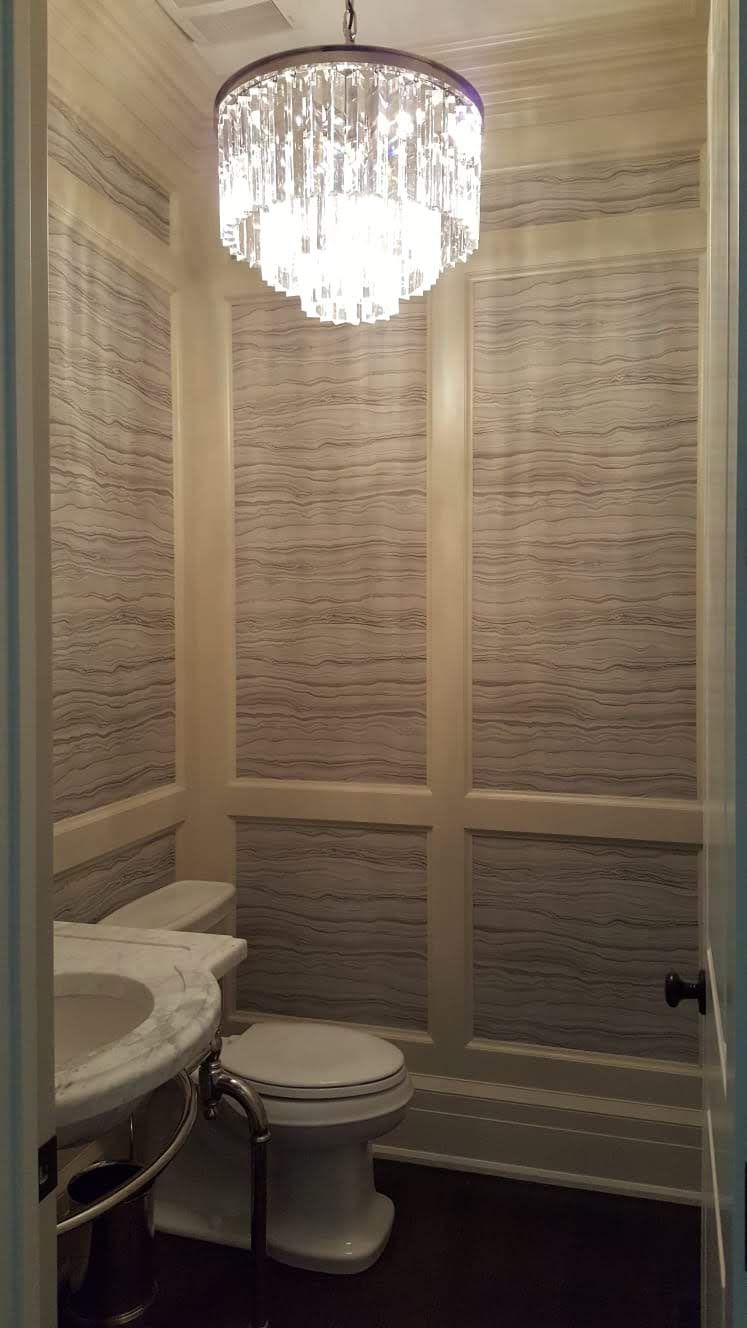 A bathroom with a toilet, sink, and chandelier.