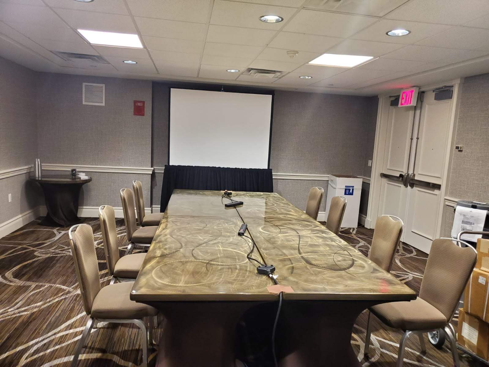 A conference room with a long table and chairs and a projector screen.
