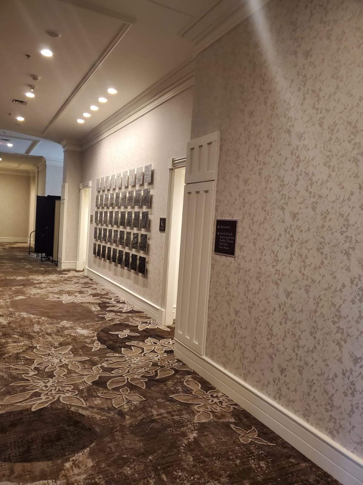 A long hallway with a carpeted floor and a wall with pictures on it.