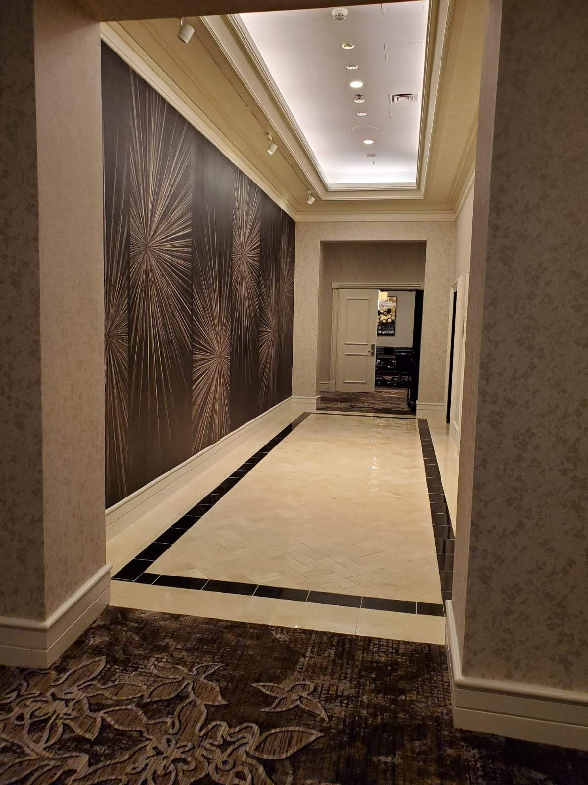 A long hallway with a painting on the wall and a marble floor.