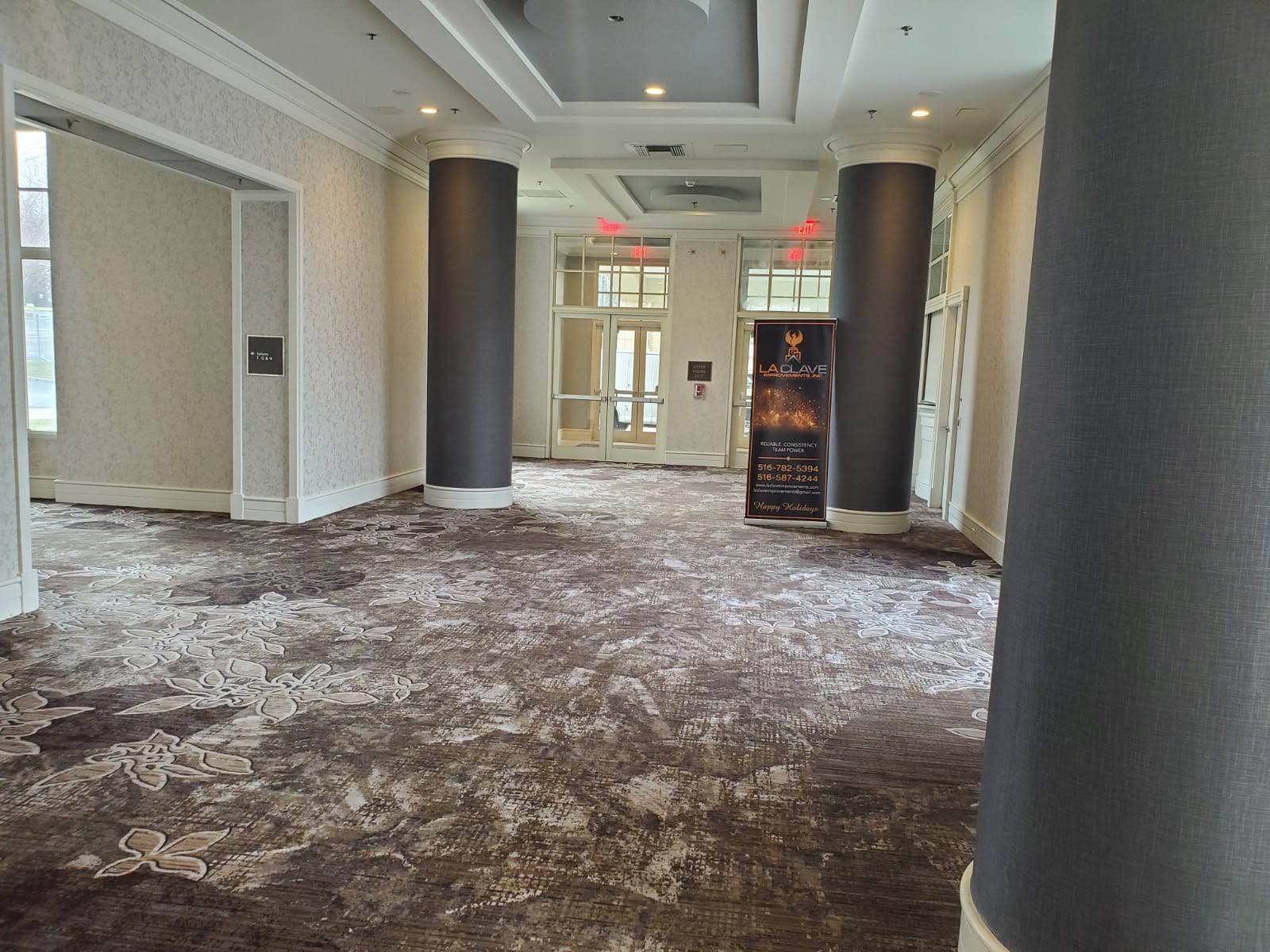 A large hallway with columns and a carpeted floor