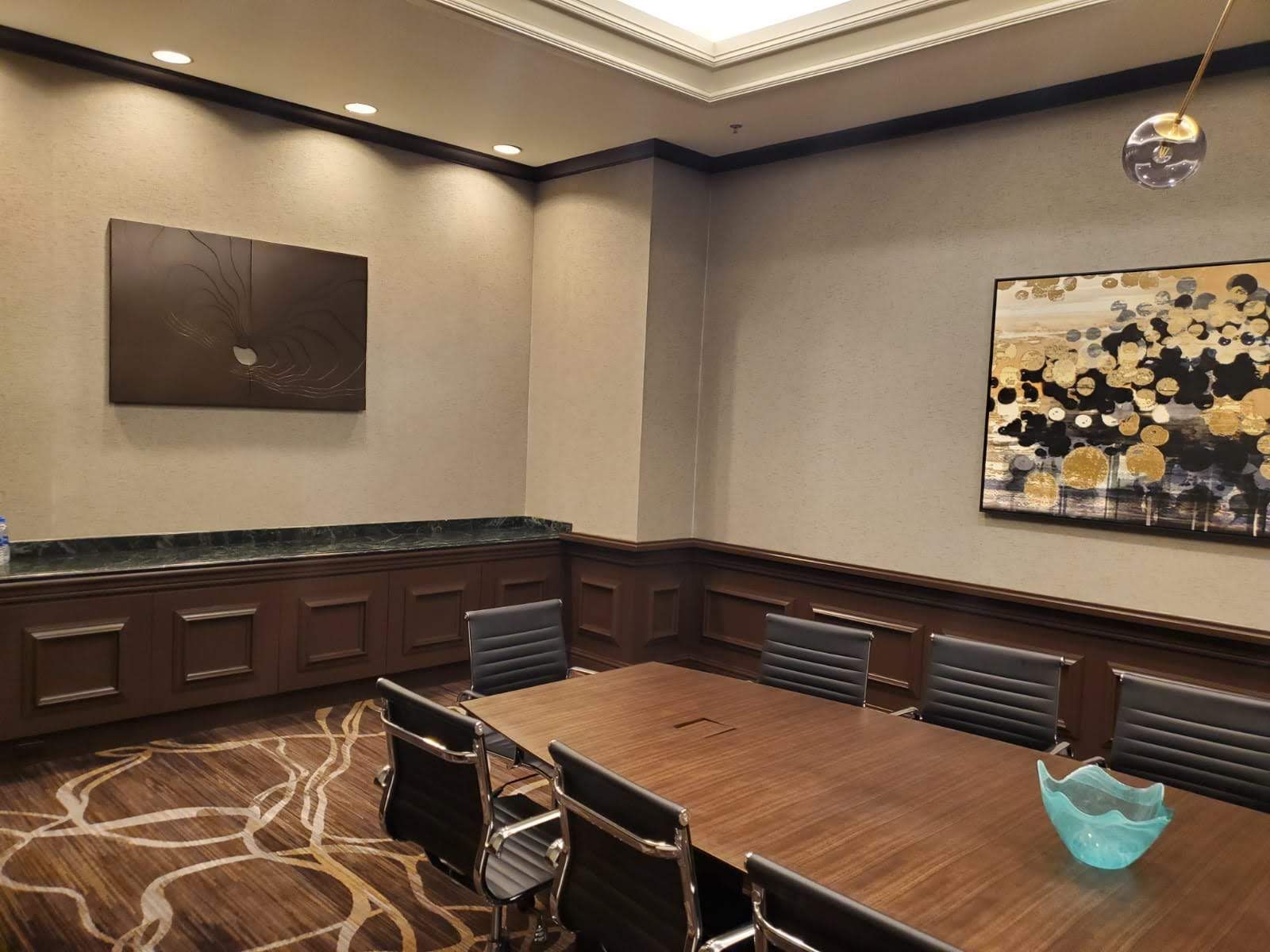 A conference room with a table and chairs and a painting on the wall.