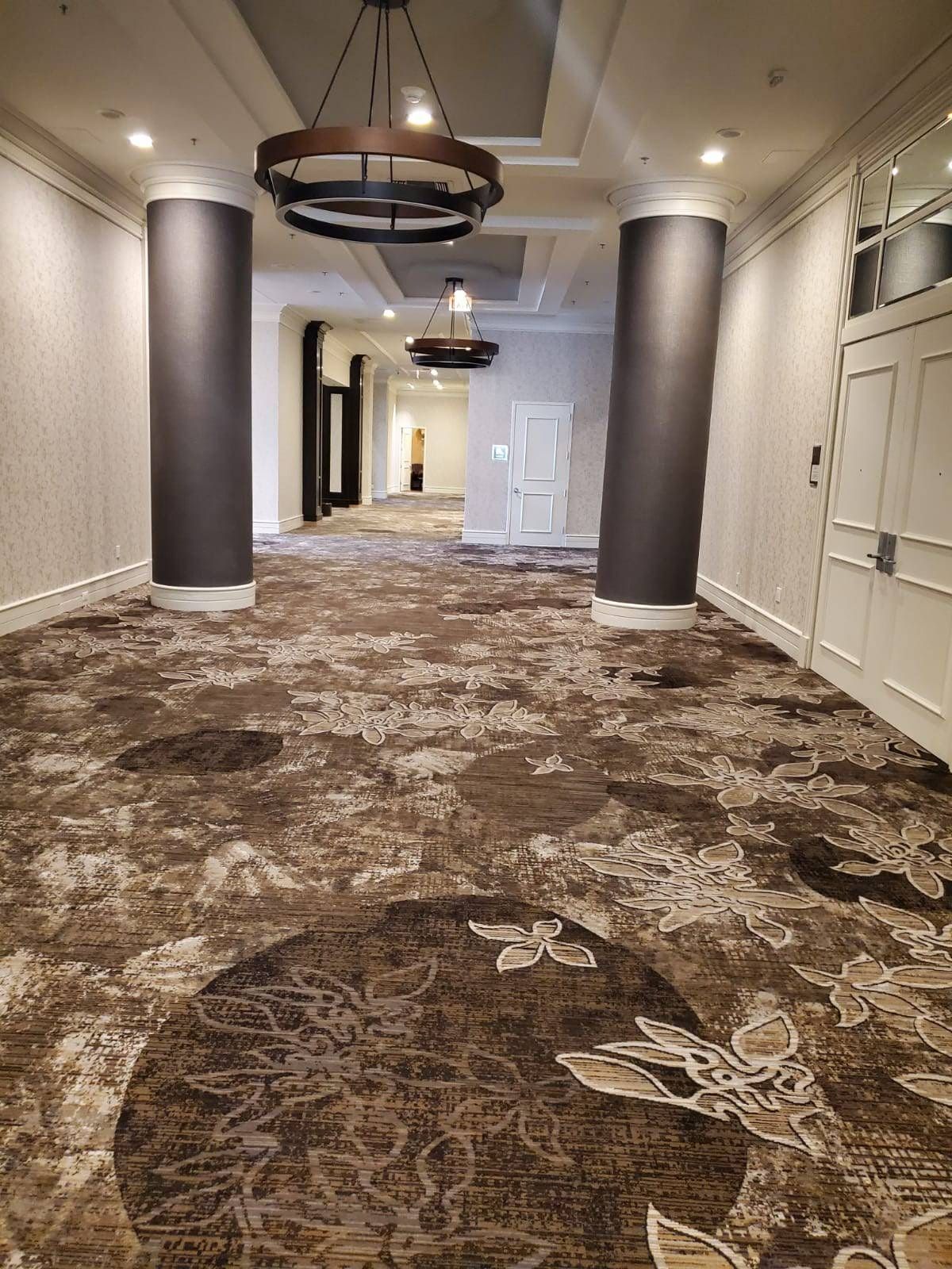A long hallway with a carpeted floor and a chandelier hanging from the ceiling.