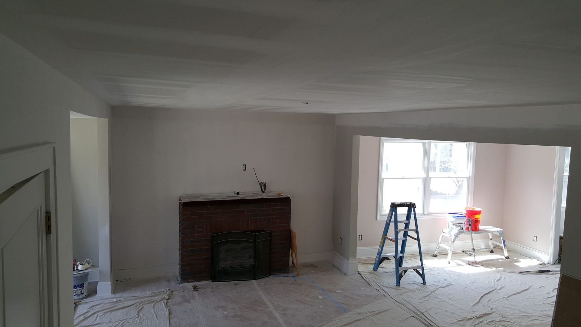 A living room with a fireplace and a ladder in it.