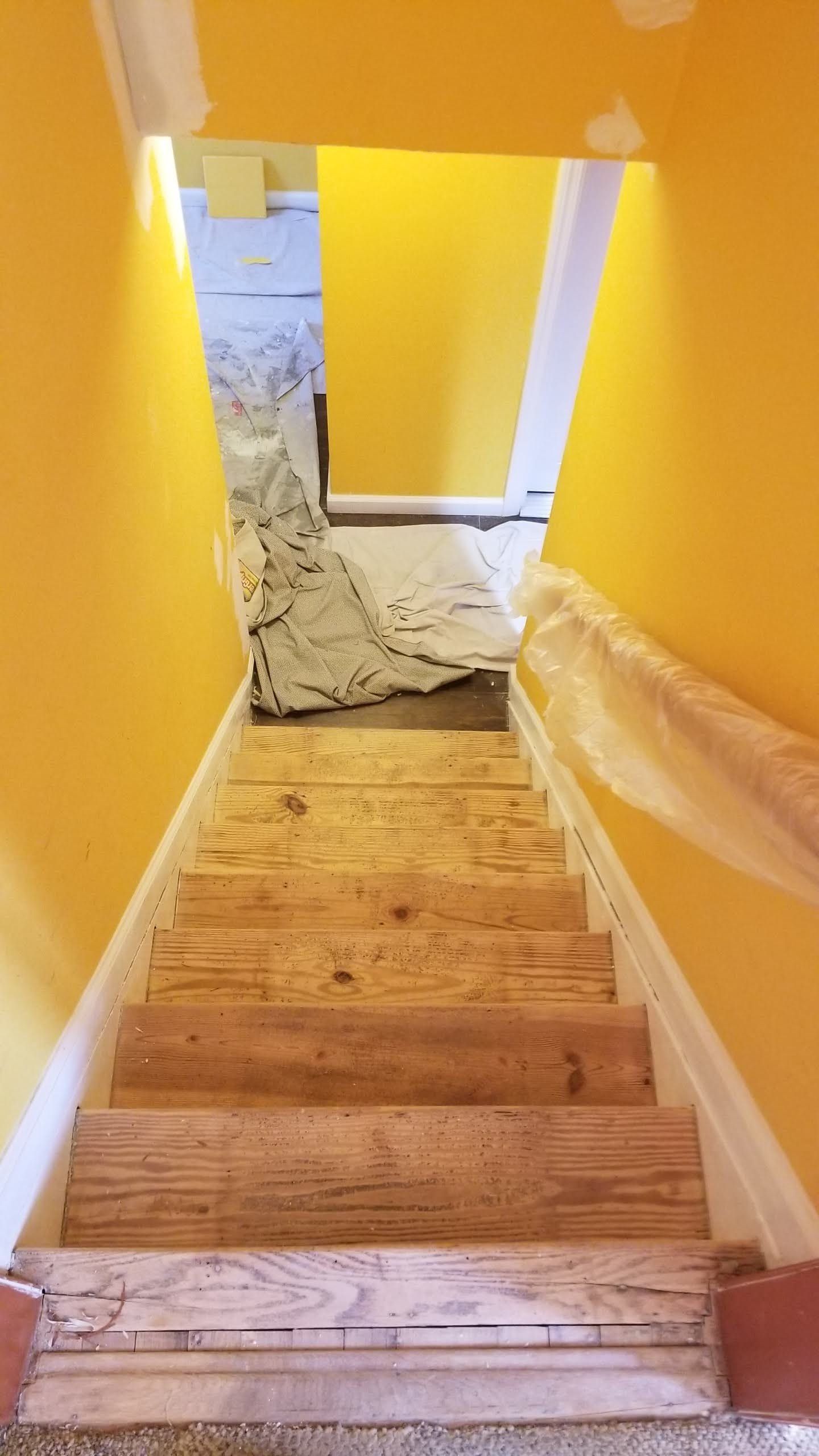 A set of wooden stairs leading up to a yellow wall.