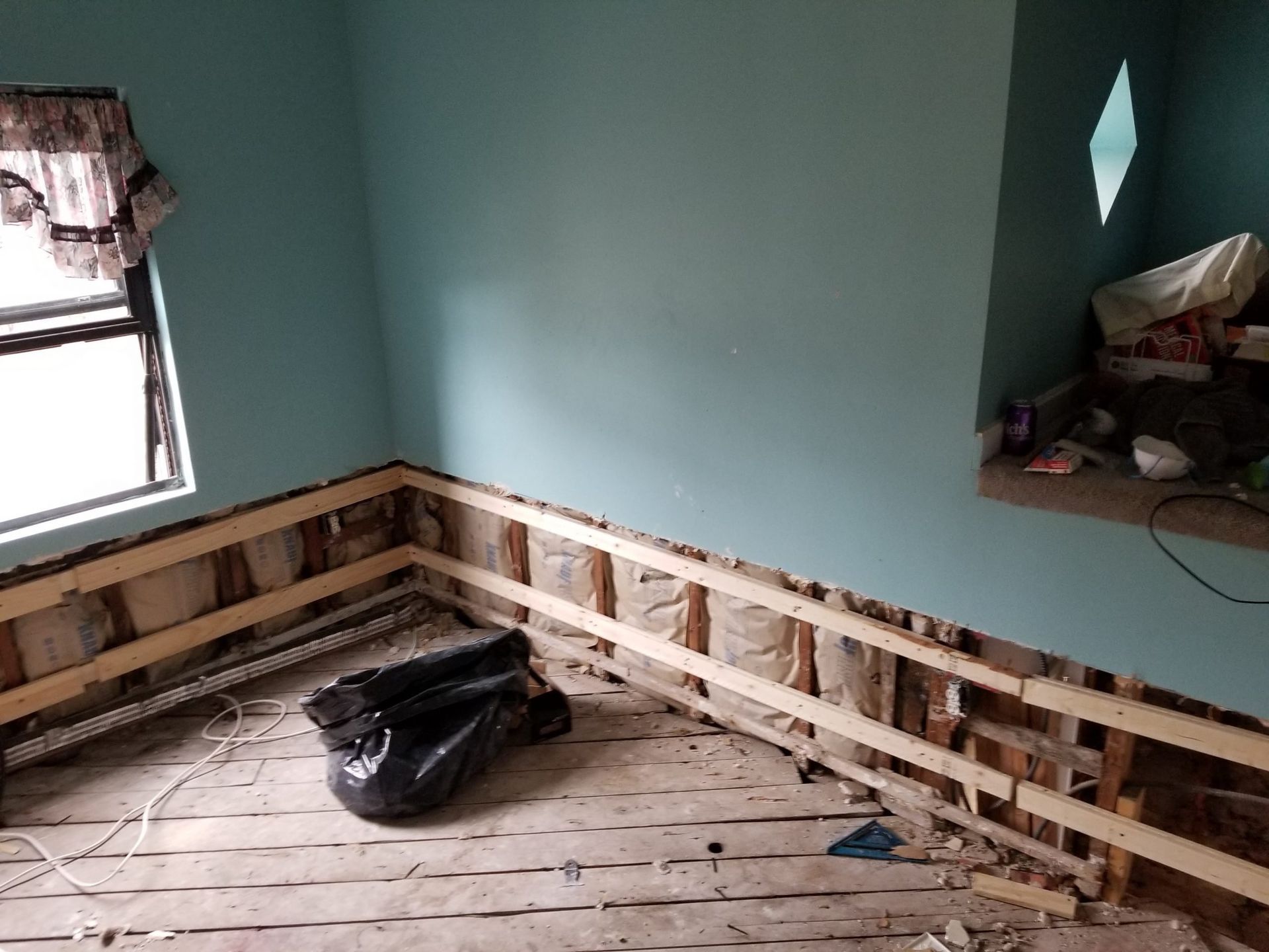 A room with a window and a black bag on the floor.