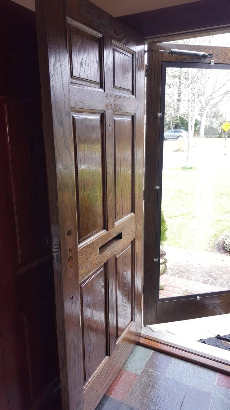 A wooden door is open to a lush green field.