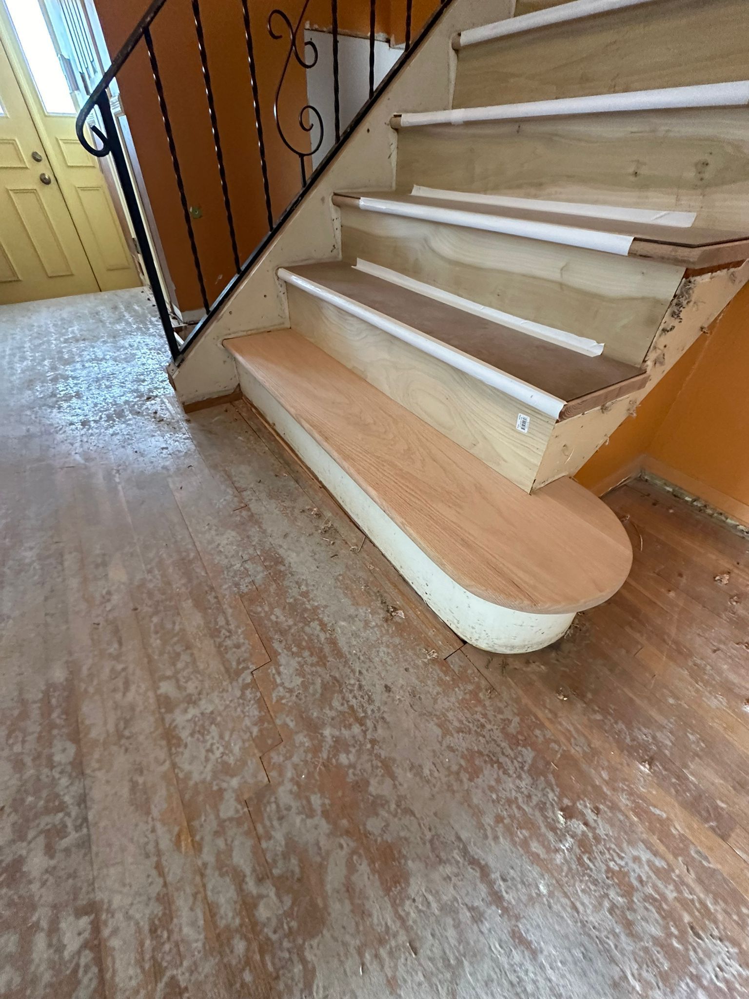 A staircase with wooden steps and a metal railing in a hallway.