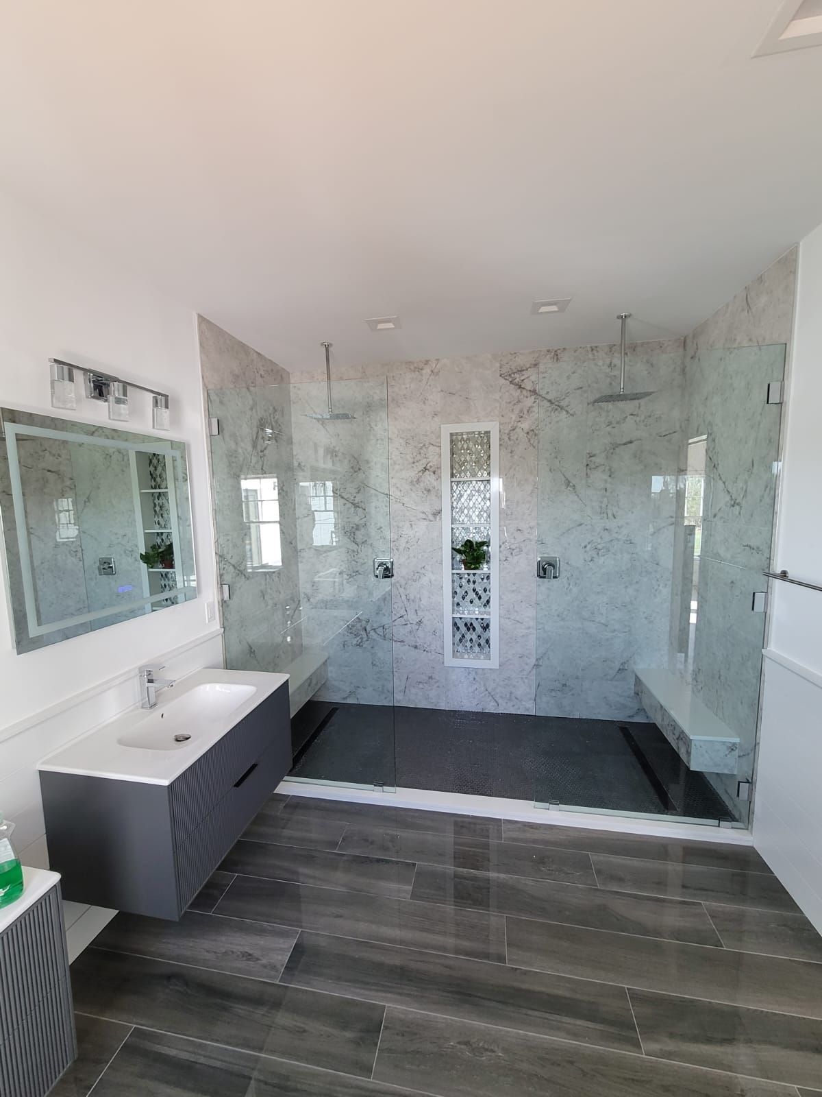 A bathroom with a sink, mirror and walk in shower.