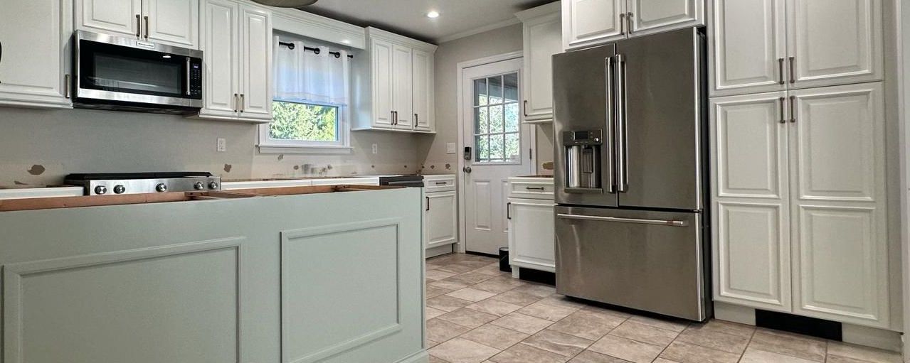 A kitchen with white cabinets, stainless steel appliances, and a tile floor.