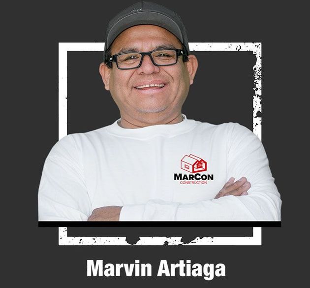 Marvin Artiaga smiling in a white shirt and black cap against a dark background