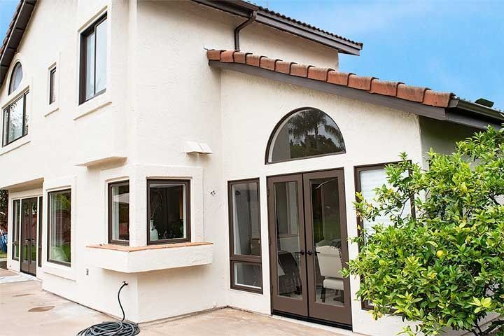 Exterior of a white two-story house with large windows, a glass door, and a tiled roof