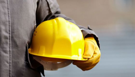 Person holding a yellow hard hat outdoors