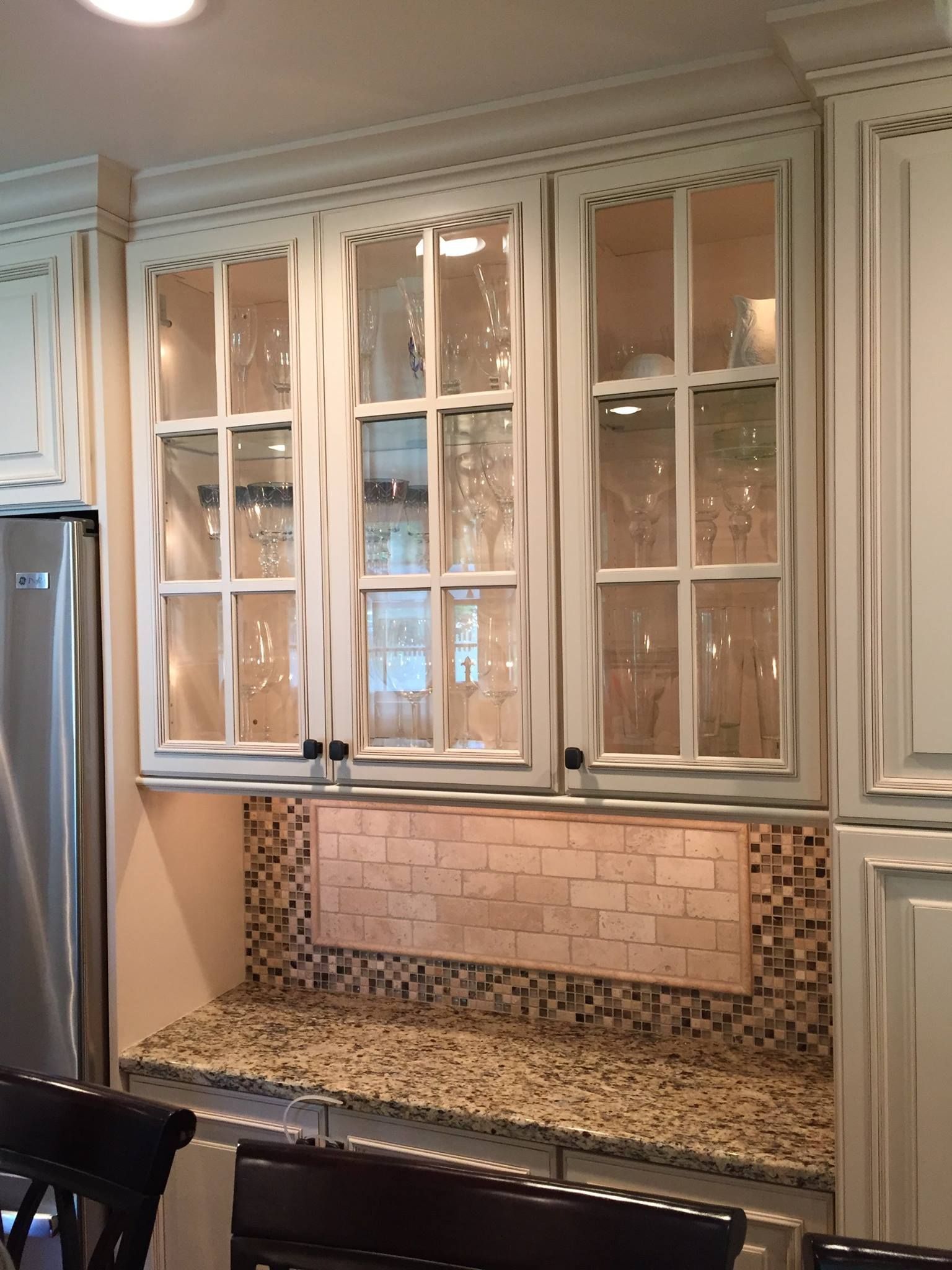 A kitchen with stainless steel appliances , granite counter tops , and glass cabinets.