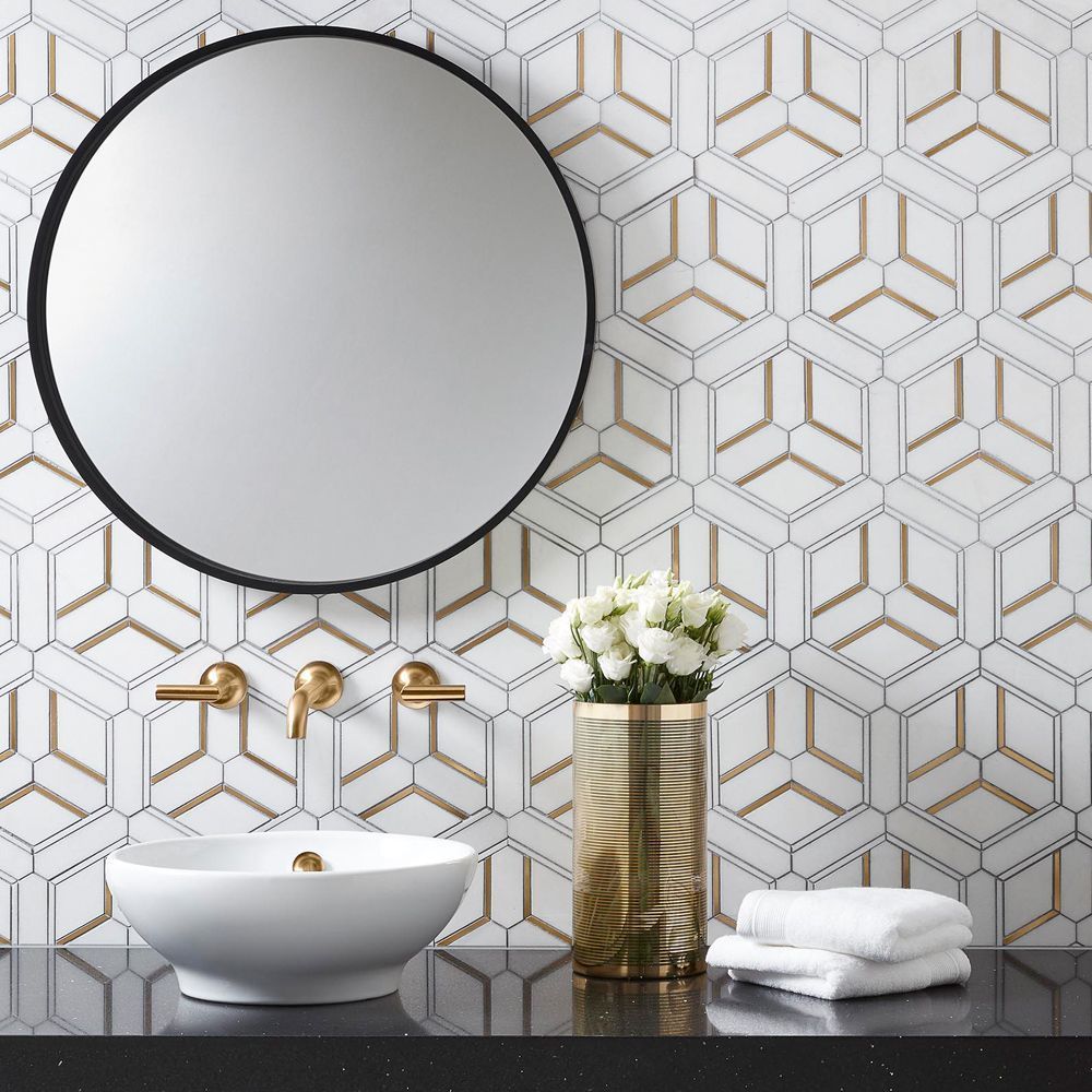 Bathroom with patterned tile wall, gold fixtures, round mirror, white sink, and flowers