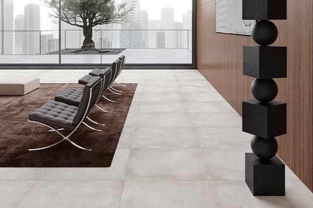 Modern waiting area with gray tile floor, brown rug, leather chairs, cityscape view, and black sculpture