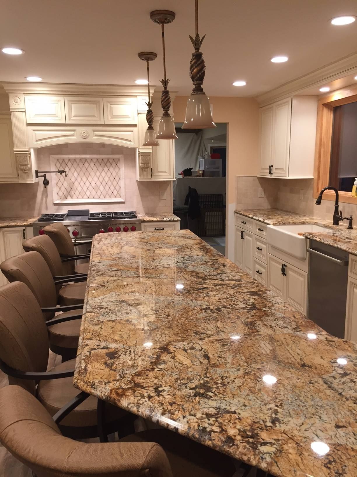 A kitchen with a large granite counter top and chairs
