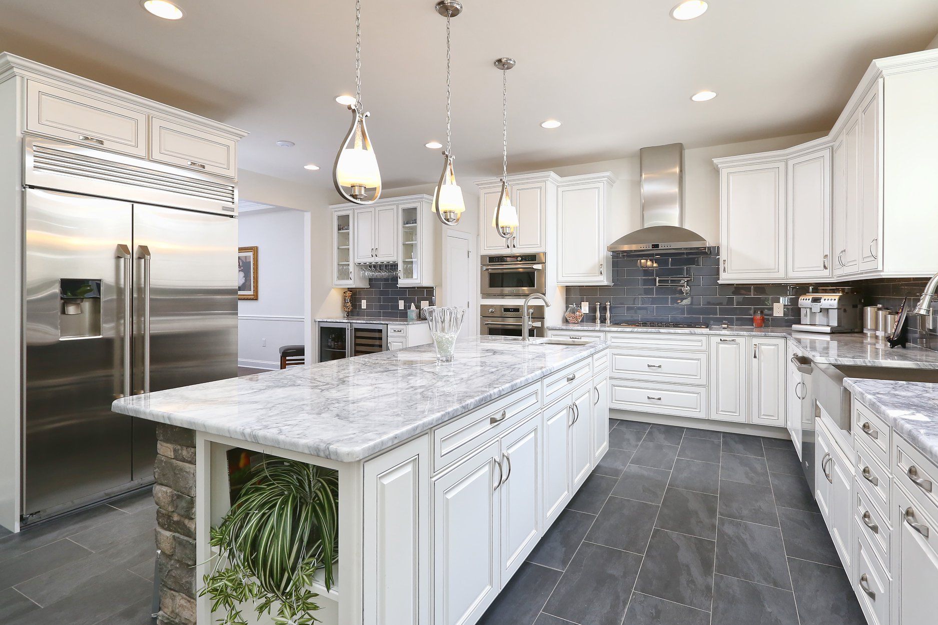 A kitchen with white cabinets , granite counter tops , stainless steel appliances and a large island.