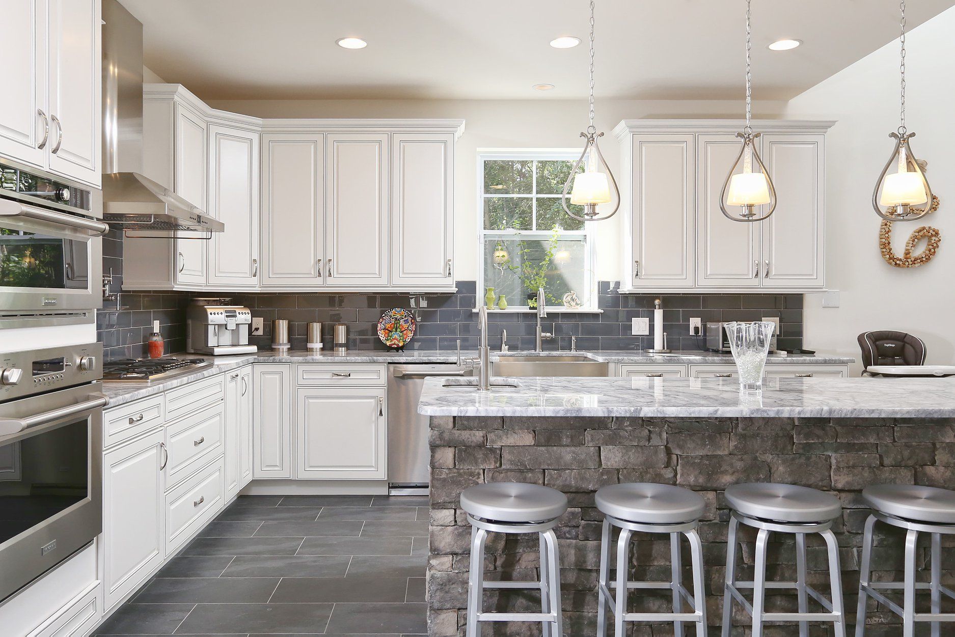 A kitchen with white cabinets , stainless steel appliances , granite counter tops and a large island.