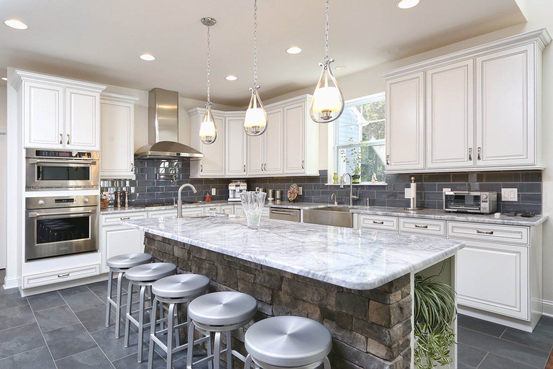 A kitchen with white cabinets and stainless steel appliances and a large island.