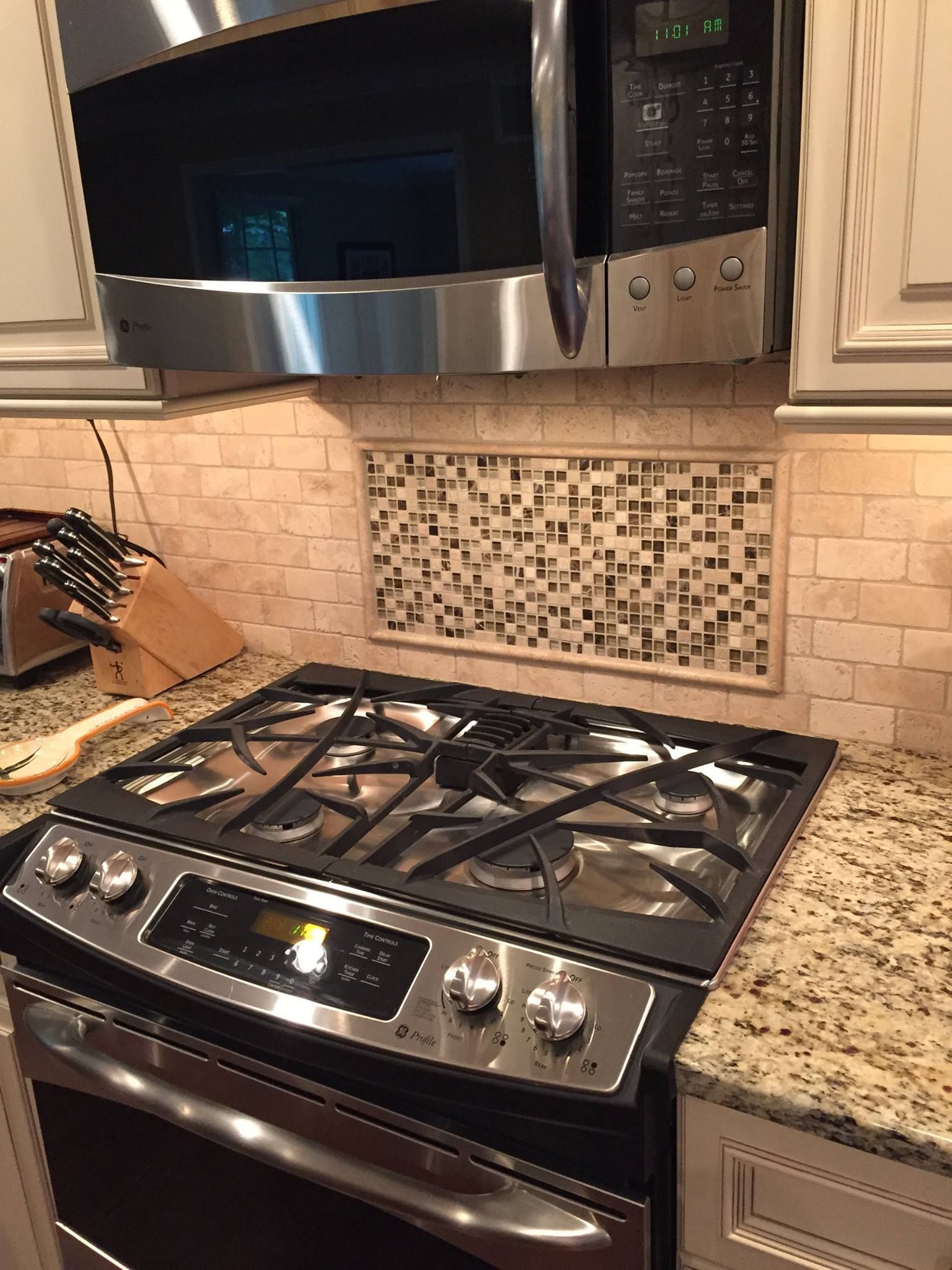 A stove top oven is sitting on top of a granite counter in a kitchen.