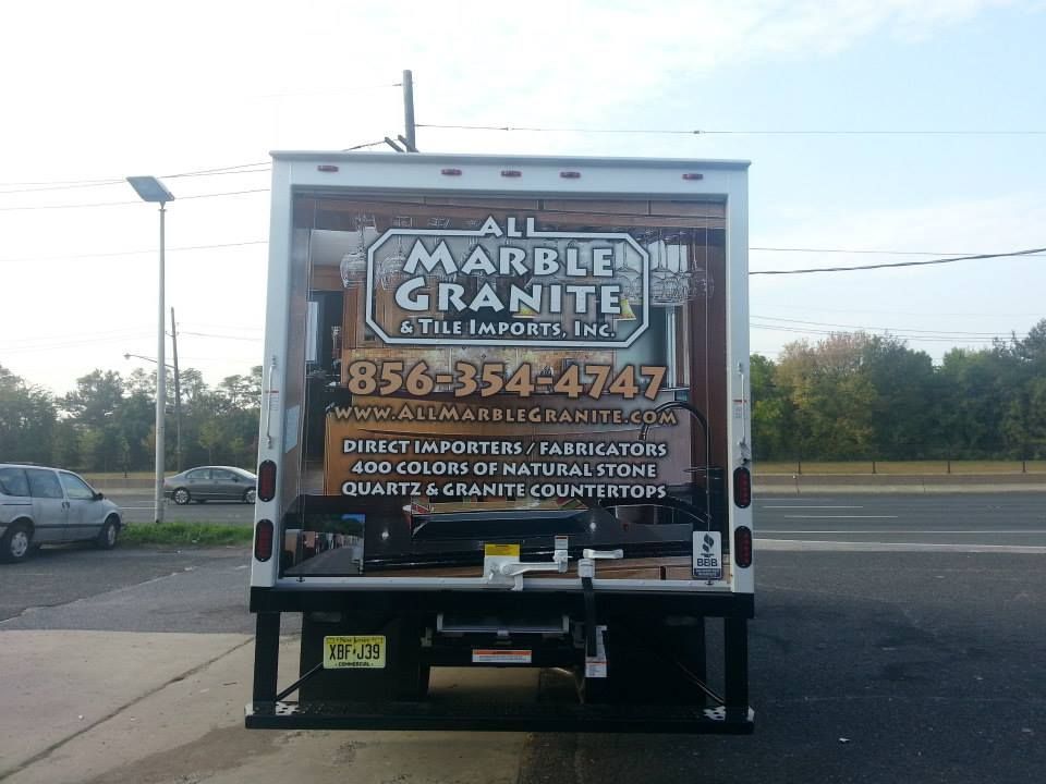 The back of a truck that says all marble granite