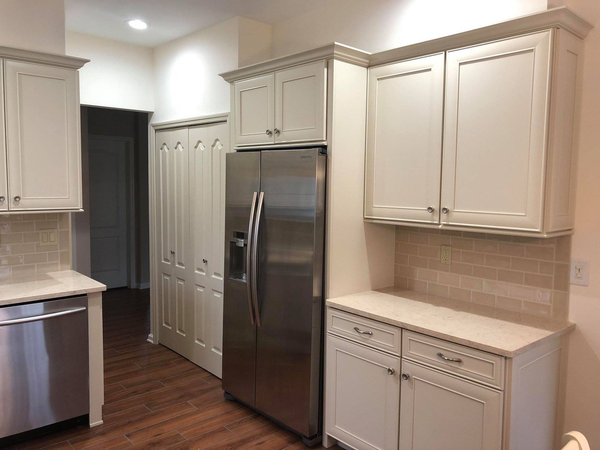 A kitchen with white cabinets and a stainless steel refrigerator.