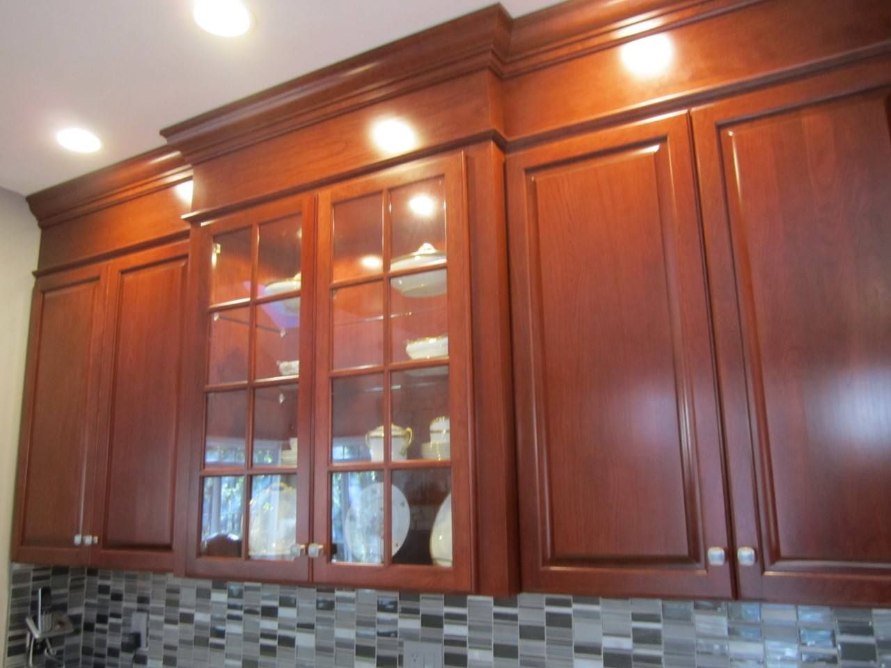 A kitchen with wooden cabinets and glass doors