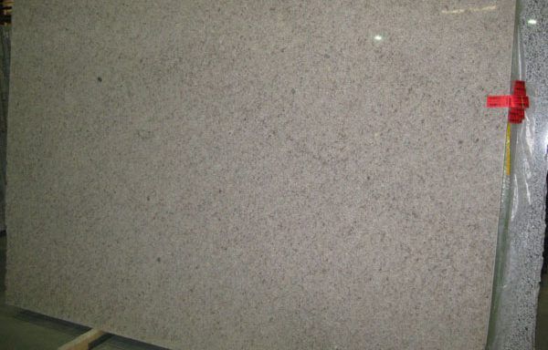 A large white granite slab is sitting on a wooden pallet in a warehouse.