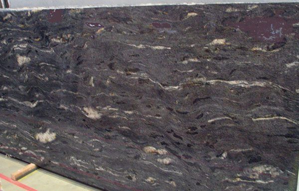 A large piece of black granite is sitting on the ground.