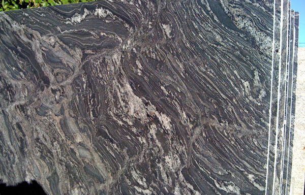 A stack of black granite slabs sitting on top of each other on a beach.
