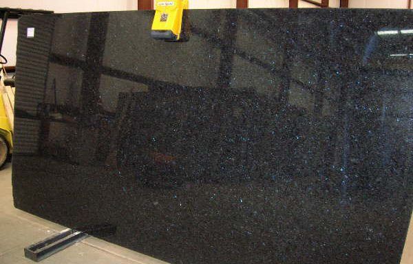 A large black granite slab is sitting on a stand in a warehouse.