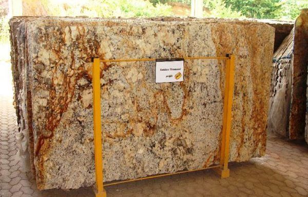 A large piece of granite is sitting on a yellow rack.