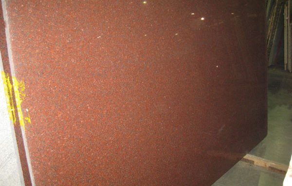 A large piece of red granite is sitting on top of a wooden pallet.