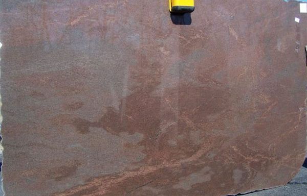 A large piece of brown granite is sitting on the ground.