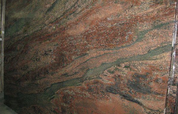 A large piece of red and green granite is sitting on a table.