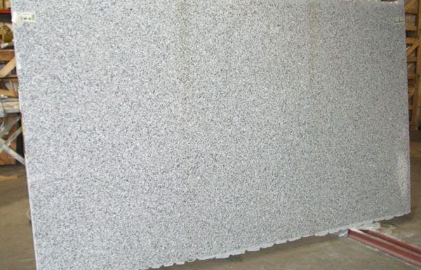 A large white granite slab is sitting on top of a concrete floor.