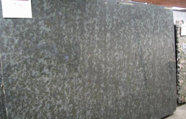 A large black granite slab is sitting in a warehouse.