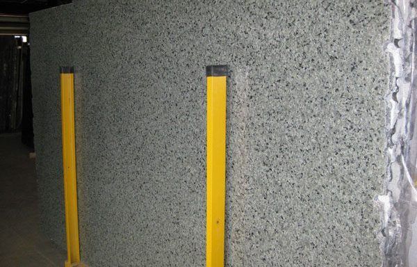 A large piece of granite is sitting next to two yellow poles.