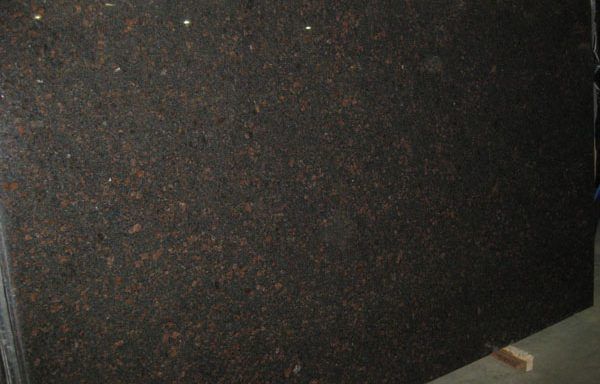 A large black granite slab is sitting on a concrete floor.