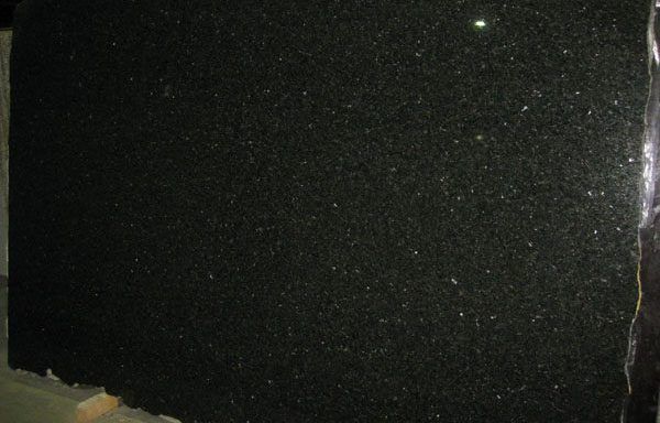 A black granite slab is sitting on top of a wooden table.