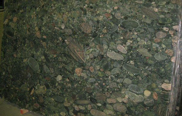 A large piece of green granite with a lot of rocks on it.
