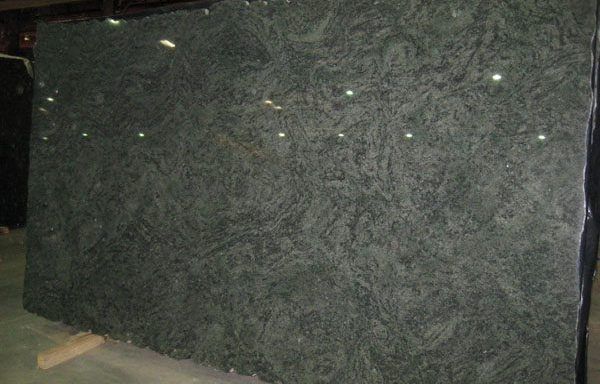 A large green granite slab is sitting on top of a concrete floor.